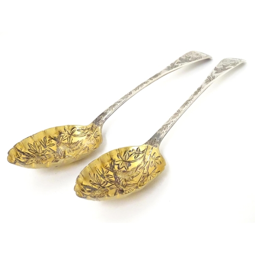 366 - A pair of white metal serving spoons with Aesthetic Movement birds amongst foliage decoration and ha... 