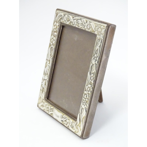 409 - A Silver fronted photograph frame with floral decoration. Import hallmarks for London 1989, importer... 