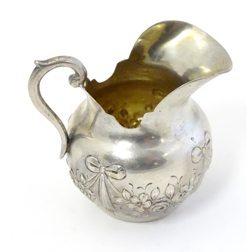 412 - A small Continental silver cream jug with bow and swag decoration. Marked under 800 and with maker’s... 