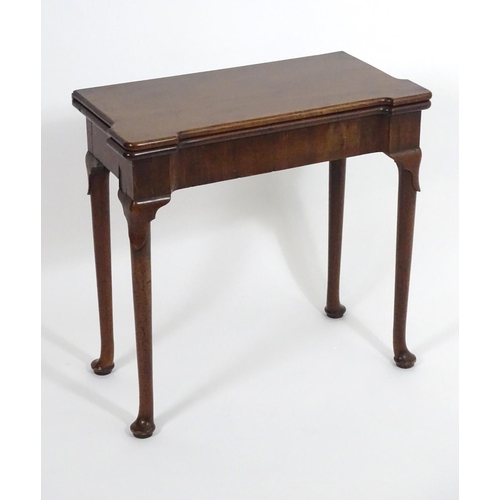 1367 - An early / mid 18thC mahogany card table with a folding top and projecting corners , standing on cab... 