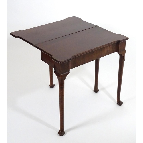 1367 - An early / mid 18thC mahogany card table with a folding top and projecting corners , standing on cab... 