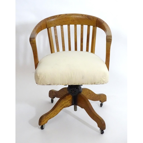 1553 - An early 20thC oak library chair with a with a bowed back and slatted supports above and an upholste... 