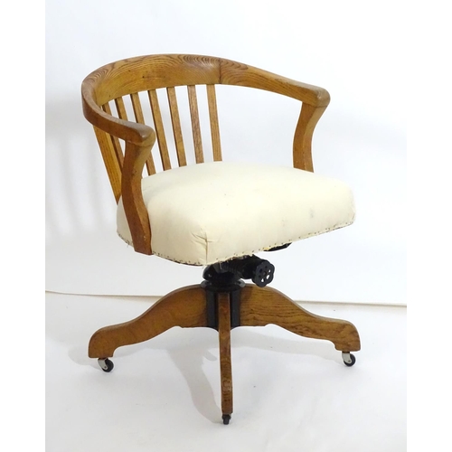 1553 - An early 20thC oak library chair with a with a bowed back and slatted supports above and an upholste... 