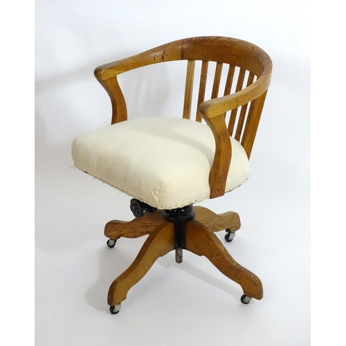 1553 - An early 20thC oak library chair with a with a bowed back and slatted supports above and an upholste... 