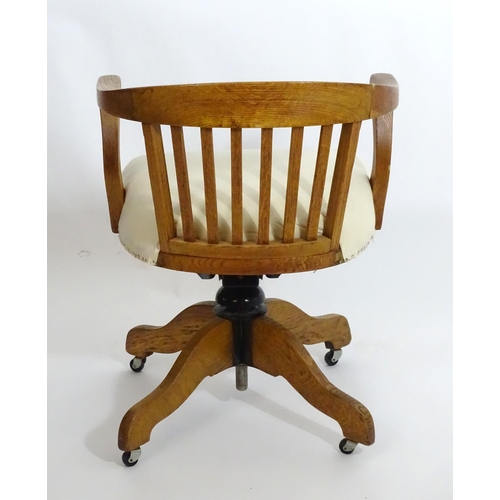 1553 - An early 20thC oak library chair with a with a bowed back and slatted supports above and an upholste... 