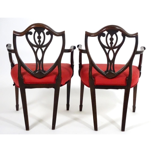 1556 - A pair of late 18thC mahogany Hepplewhite carver chairs with shield shaped backrests above pierced s... 