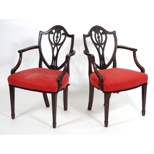 1556 - A pair of late 18thC mahogany Hepplewhite carver chairs with shield shaped backrests above pierced s... 