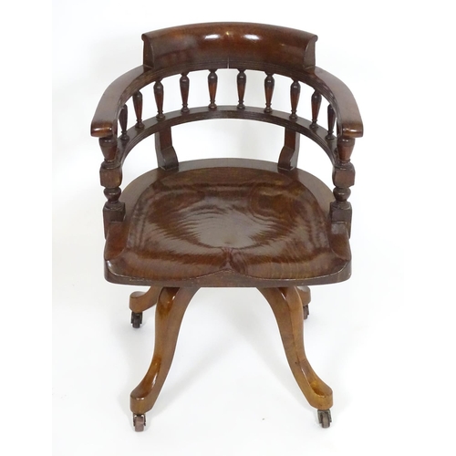 1395 - An early 20thC oak desk chair with a bowed backrest and turned spindle supports above a saddle seat ... 