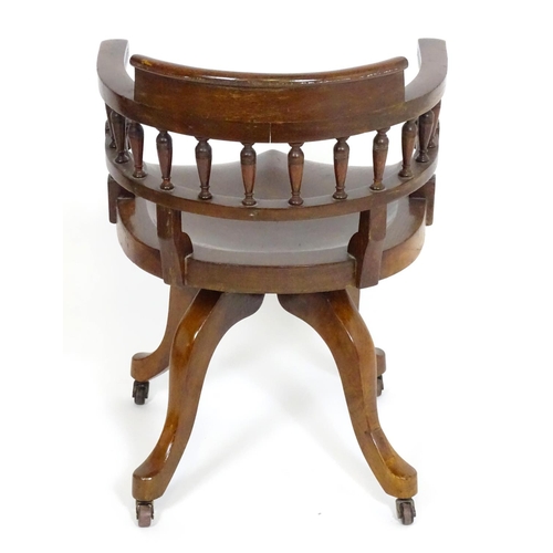 1395 - An early 20thC oak desk chair with a bowed backrest and turned spindle supports above a saddle seat ... 