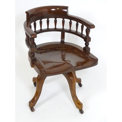 1395 - An early 20thC oak desk chair with a bowed backrest and turned spindle supports above a saddle seat ... 