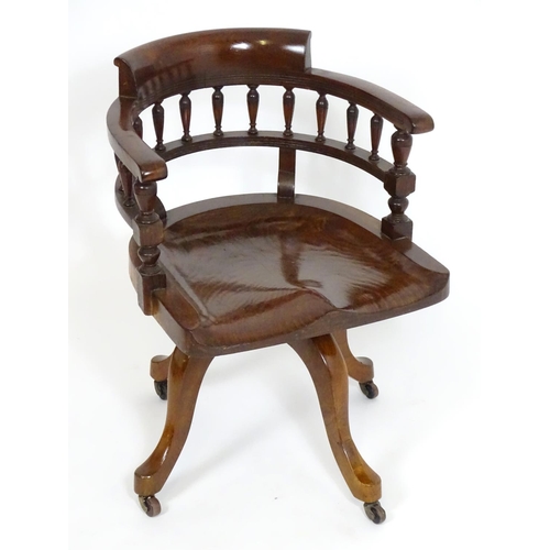 1395 - An early 20thC oak desk chair with a bowed backrest and turned spindle supports above a saddle seat ... 