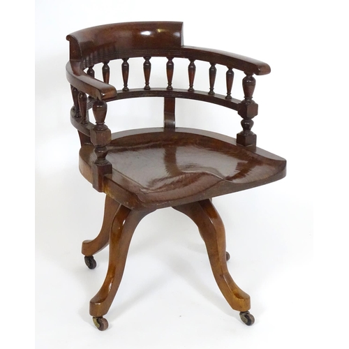 1395 - An early 20thC oak desk chair with a bowed backrest and turned spindle supports above a saddle seat ... 