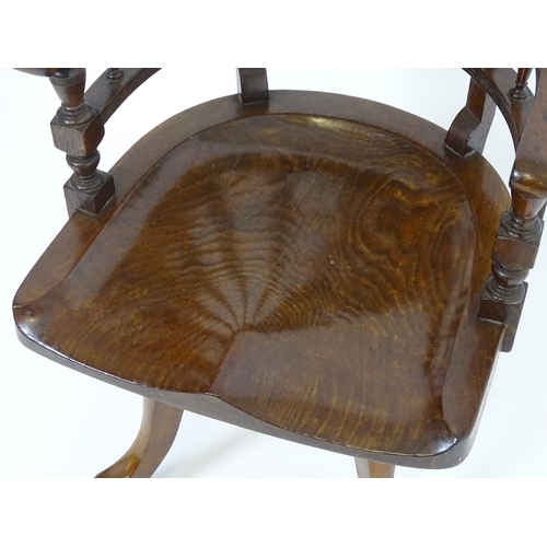 1395 - An early 20thC oak desk chair with a bowed backrest and turned spindle supports above a saddle seat ... 