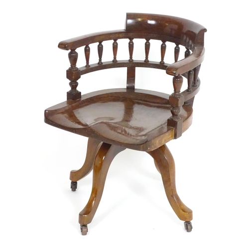 1395 - An early 20thC oak desk chair with a bowed backrest and turned spindle supports above a saddle seat ... 