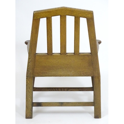 1396 - An Arts and Crafts oak throne chair with a pointed, slatted backrest and a chamfered frame and curve... 