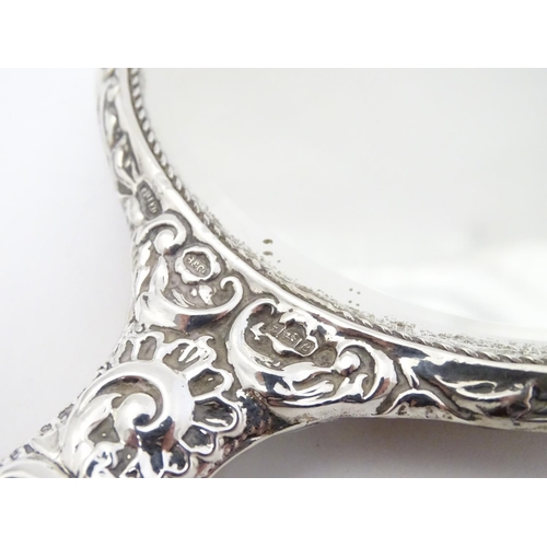 415 - A silver handled mirror with embossed decoration, hallmarked Birmingham 1977, maker W. I. Broadway &... 