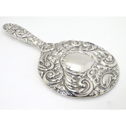 415 - A silver handled mirror with embossed decoration, hallmarked Birmingham 1977, maker W. I. Broadway &... 