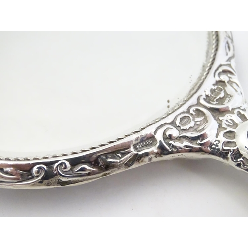 415 - A silver handled mirror with embossed decoration, hallmarked Birmingham 1977, maker W. I. Broadway &... 