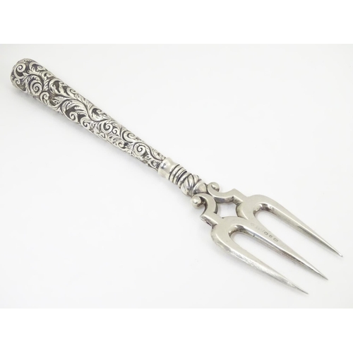 440 - A Victorian silver bread fork with an embossed handle, the central tine hallmarked Birmingham 1898, ... 