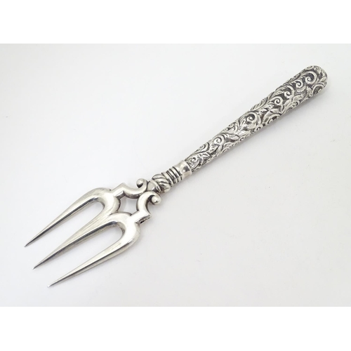 440 - A Victorian silver bread fork with an embossed handle, the central tine hallmarked Birmingham 1898, ... 