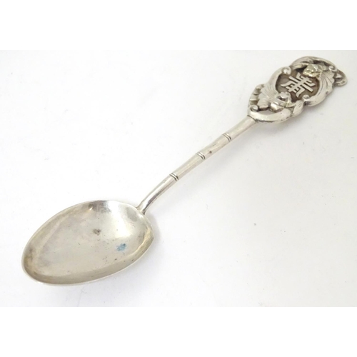 459 - An Oriental white metal teaspoon with stylised bamboo handle surmounted by bat decoration. Marked wi... 