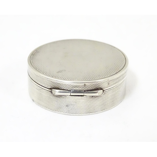 465 - A Continental .935 sterling silver pill box of circular form with engine turned decoration and gilde... 