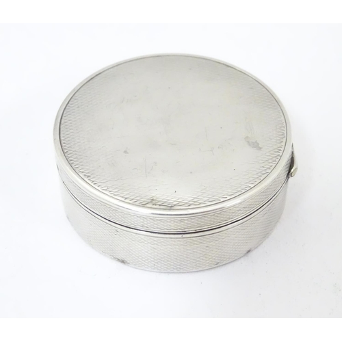 465 - A Continental .935 sterling silver pill box of circular form with engine turned decoration and gilde... 