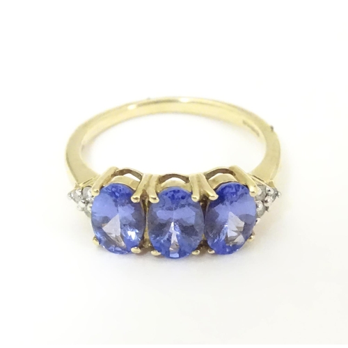 502 - A 9ct gold ring set with three oval tanzanite flanked by three diamonds to shoulders. Ring size appr... 