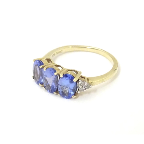 502 - A 9ct gold ring set with three oval tanzanite flanked by three diamonds to shoulders. Ring size appr... 