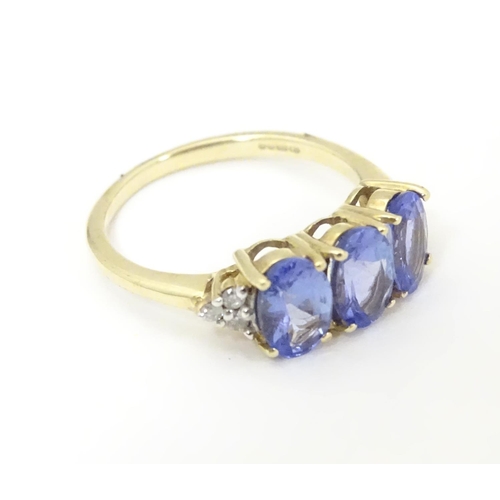 502 - A 9ct gold ring set with three oval tanzanite flanked by three diamonds to shoulders. Ring size appr... 