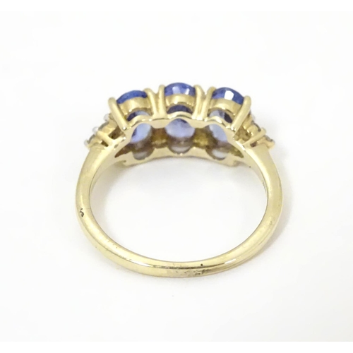 502 - A 9ct gold ring set with three oval tanzanite flanked by three diamonds to shoulders. Ring size appr... 