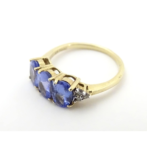 502 - A 9ct gold ring set with three oval tanzanite flanked by three diamonds to shoulders. Ring size appr... 