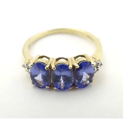 502 - A 9ct gold ring set with three oval tanzanite flanked by three diamonds to shoulders. Ring size appr... 