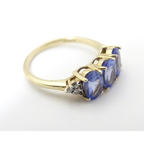 502 - A 9ct gold ring set with three oval tanzanite flanked by three diamonds to shoulders. Ring size appr... 