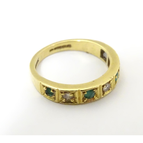 503 - An 18ct gold ring set with 4 emeralds and 3 diamonds. Ring size approx K