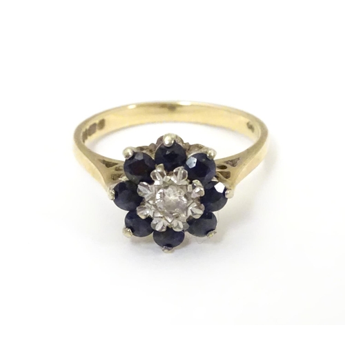 505 - A 9ct gold ring set with central diamond bordered by 8 blue spinel in a daisy setting. Ring size app... 