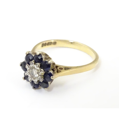 505 - A 9ct gold ring set with central diamond bordered by 8 blue spinel in a daisy setting. Ring size app... 