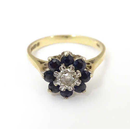 505 - A 9ct gold ring set with central diamond bordered by 8 blue spinel in a daisy setting. Ring size app... 