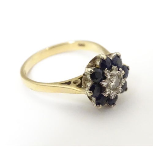 505 - A 9ct gold ring set with central diamond bordered by 8 blue spinel in a daisy setting. Ring size app... 