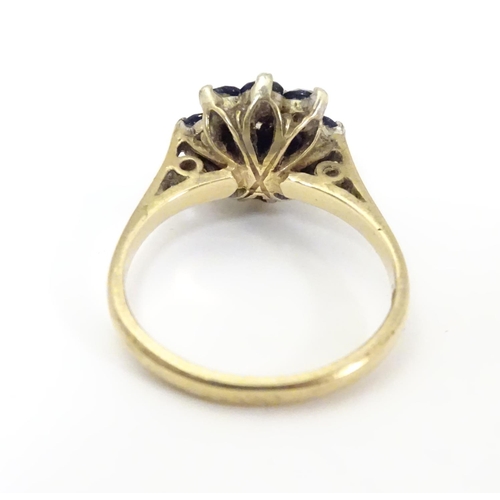 505 - A 9ct gold ring set with central diamond bordered by 8 blue spinel in a daisy setting. Ring size app... 