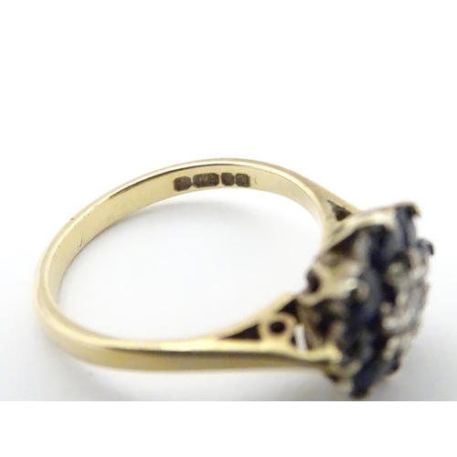 505 - A 9ct gold ring set with central diamond bordered by 8 blue spinel in a daisy setting. Ring size app... 