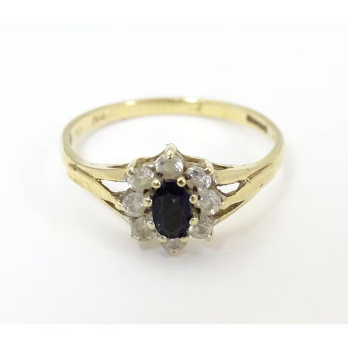 506 - A 9ct gold sapphire floral cluster ring bordered by white stones. Ring size approx N 1/2