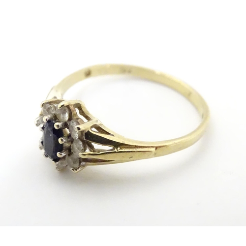 506 - A 9ct gold sapphire floral cluster ring bordered by white stones. Ring size approx N 1/2