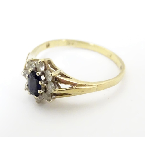 506 - A 9ct gold sapphire floral cluster ring bordered by white stones. Ring size approx N 1/2