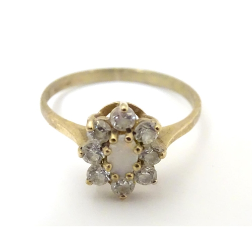 507 - A 9ct gold ring set with opal like cabochon bordered by white stones. Ring size approx L