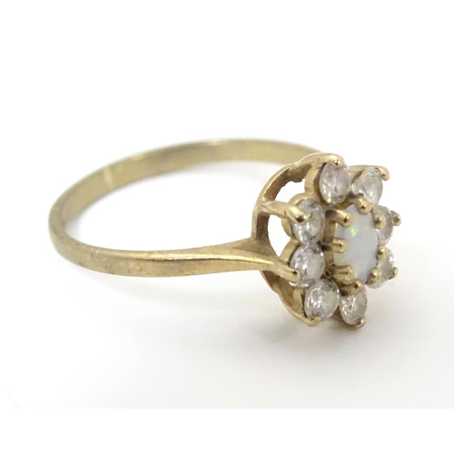 507 - A 9ct gold ring set with opal like cabochon bordered by white stones. Ring size approx L