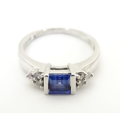 513 - A 9ct white gold ring set with central sapphire flanked by diamonds. Ring size approx L 1/2