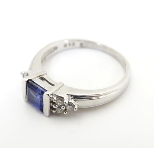 513 - A 9ct white gold ring set with central sapphire flanked by diamonds. Ring size approx L 1/2