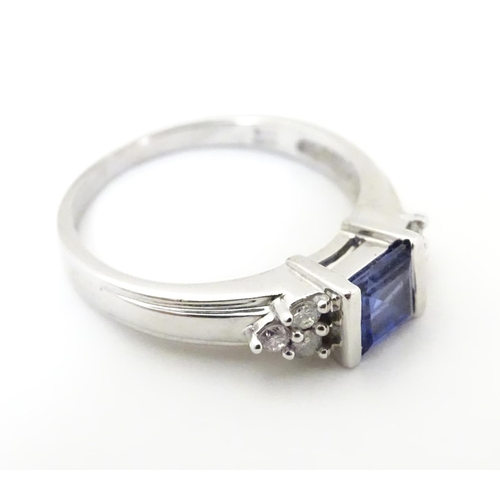 513 - A 9ct white gold ring set with central sapphire flanked by diamonds. Ring size approx L 1/2