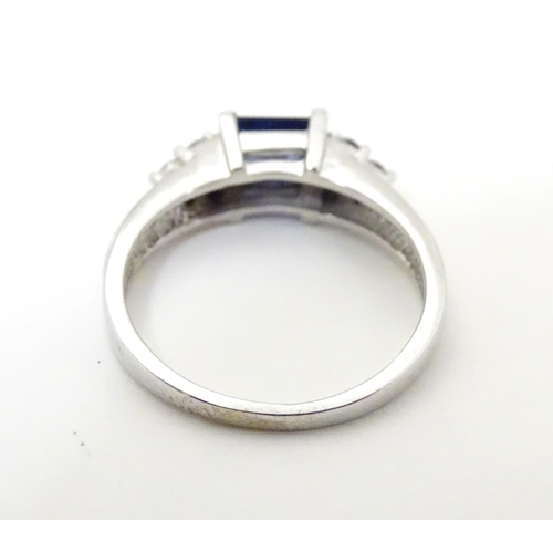 513 - A 9ct white gold ring set with central sapphire flanked by diamonds. Ring size approx L 1/2